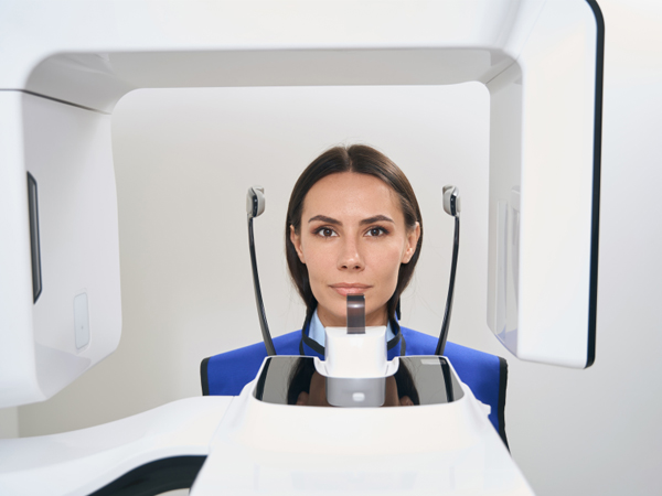 Woman undergoing dental scan in modern imaging equipment at dental clinic.