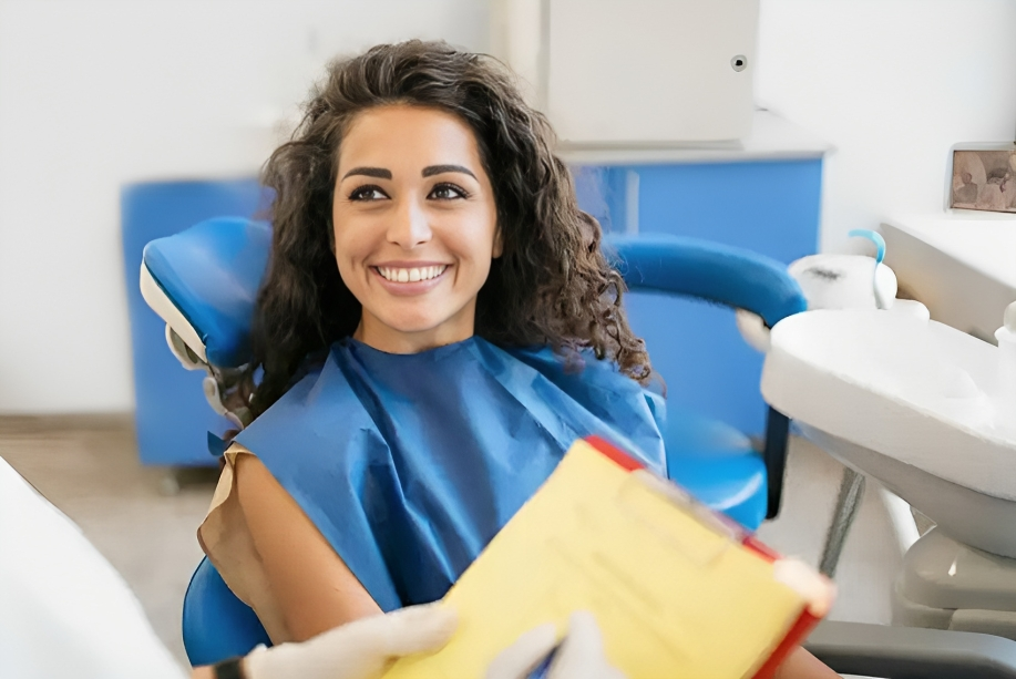 Woman in dental bib smiling at dental office chair, West River Dental Care setting.